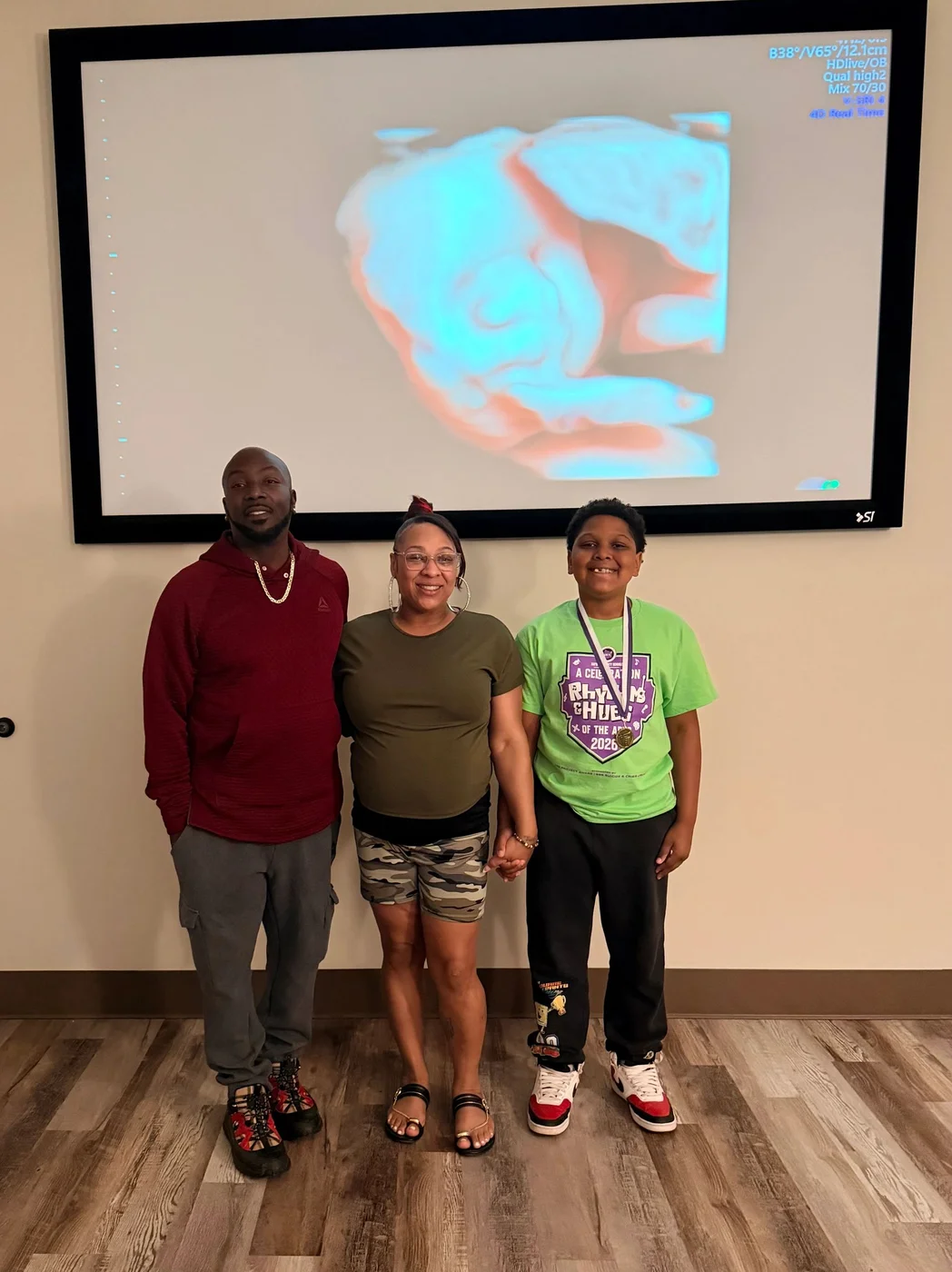 Three guests standing beneath a large screen displaying a 4D ultrasound in the studio