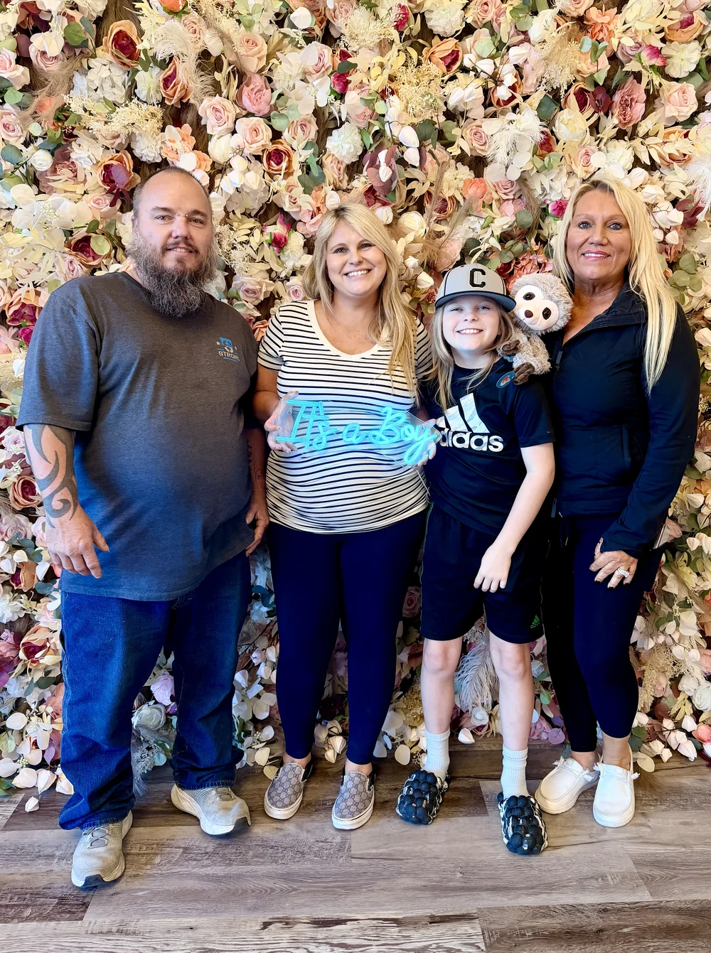 Four studio guests celebrating together with an ultrasound keepsake in front of the flower wall